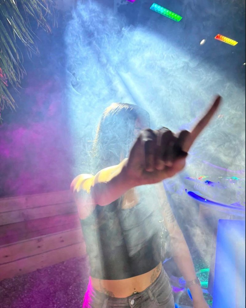 Tanzende Person im Nebel und bunten Licht vor dem DJ-Pult